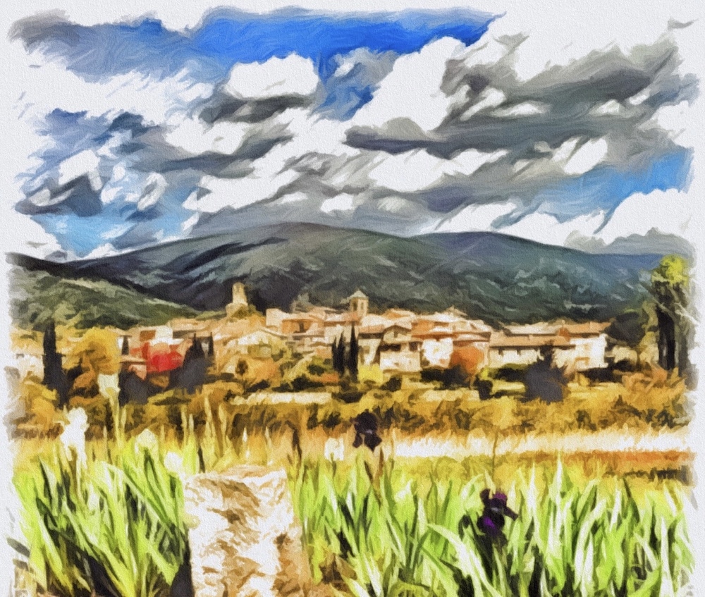 Vue d'un village de Lourmarin avec des collines et un ciel nuageux en arrière-plan.